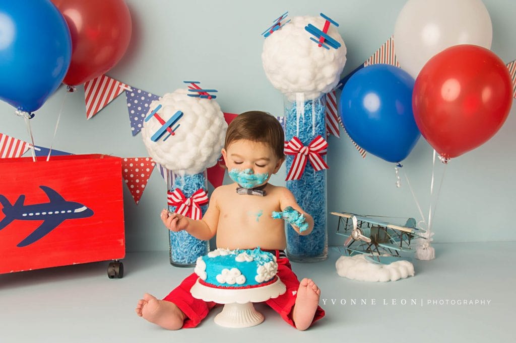 one year old boy smiling and looking at his cake as if he is really enjoying it
