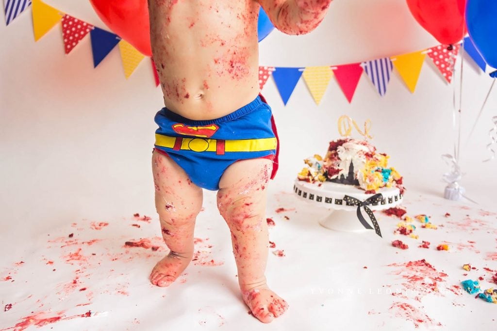closeup of baby standing up with legs covered in cake during the finale of his cake smash photo session in nj baby photography studio