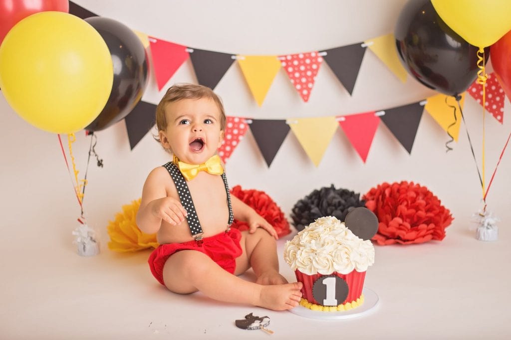 baby boy laughing after tasting his cake during his first birthday cake smash photo session