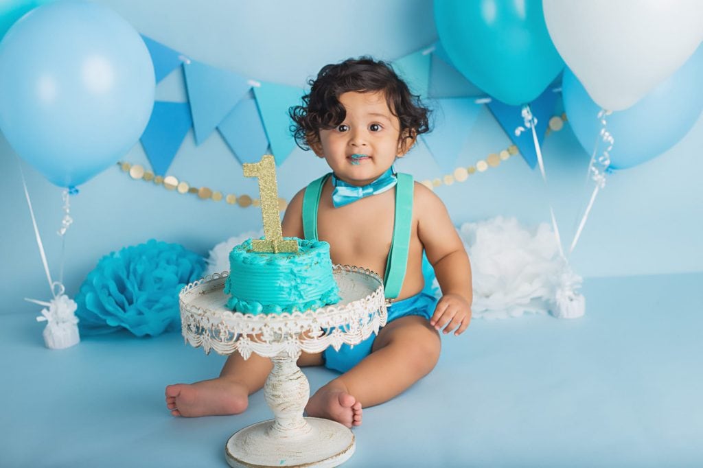 baby boy with a surprised look on his face after tasting his cake for the first time during his cake smash photo shoot.