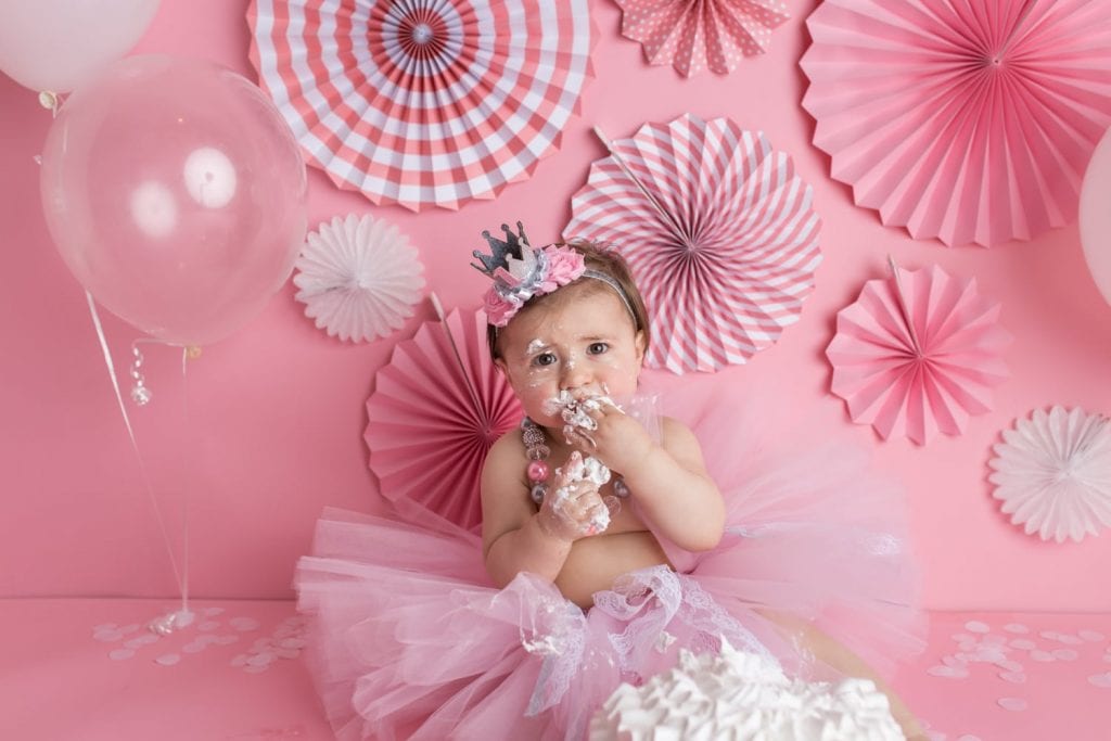 Baby girl with face covered in frosting during her cake smash shoots in New Jersey
