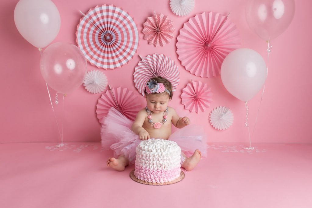 Girly cake smash setup with pink and white and baby girl in a tutu skirt
