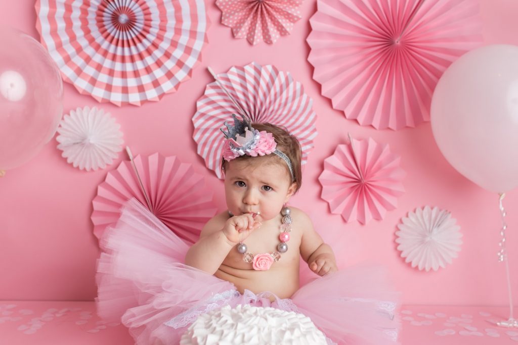 Baby girl putting frosting in her mouth during a cake smash photoshoot at Yvonne Leon Photography