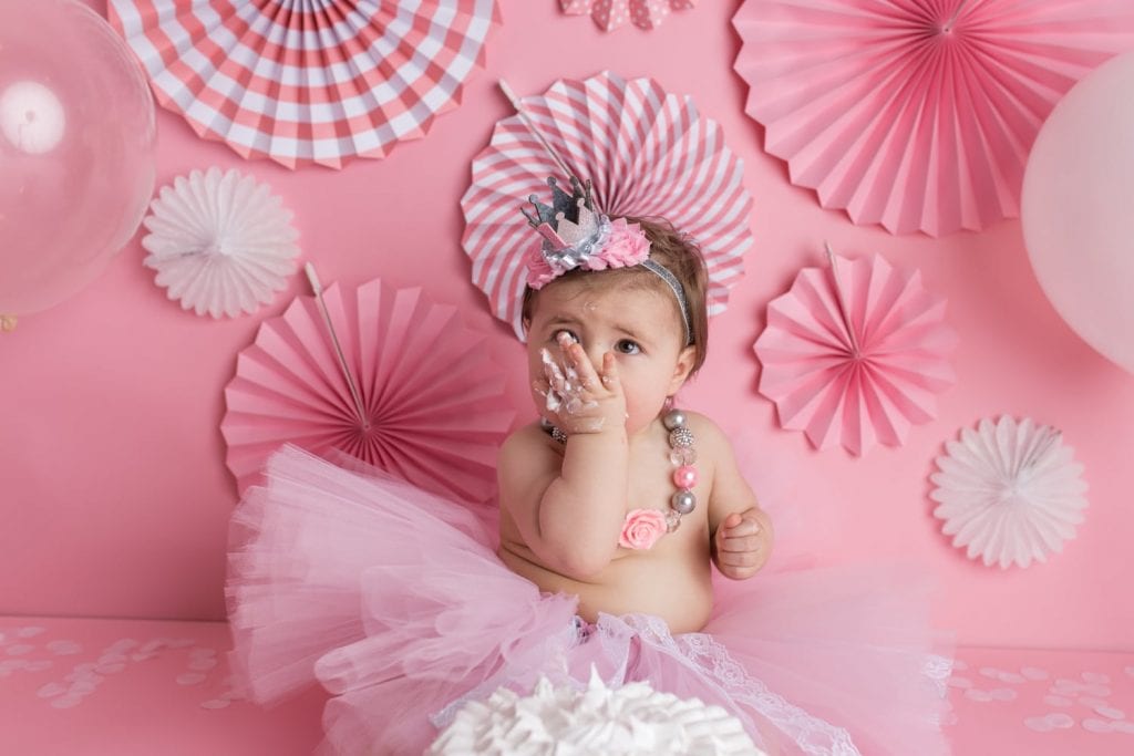 studio portrait session of a girly cake smash with pink and white