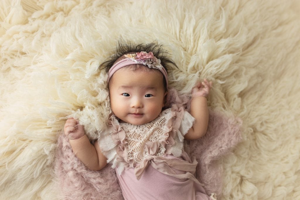 Baby girl laying on fluffy rug for 100 days photo session.