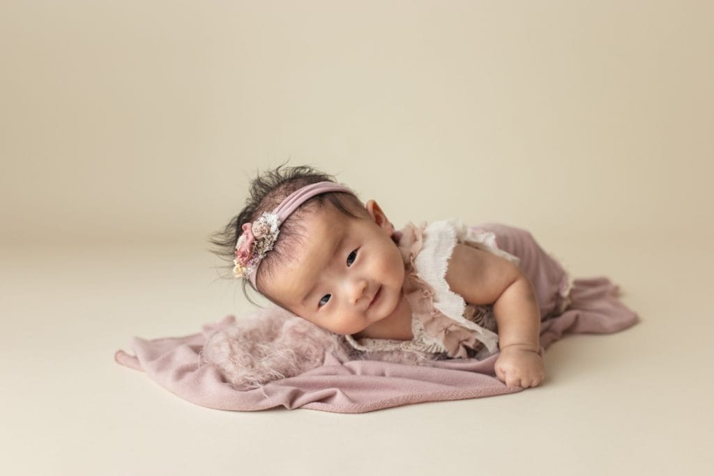 Asian baby doing tummy time for 100 Days photo session.