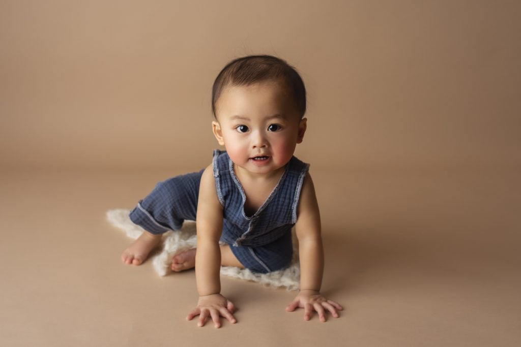baby milestone portrait of baby boy sitting up and about to crawl toward the camera.