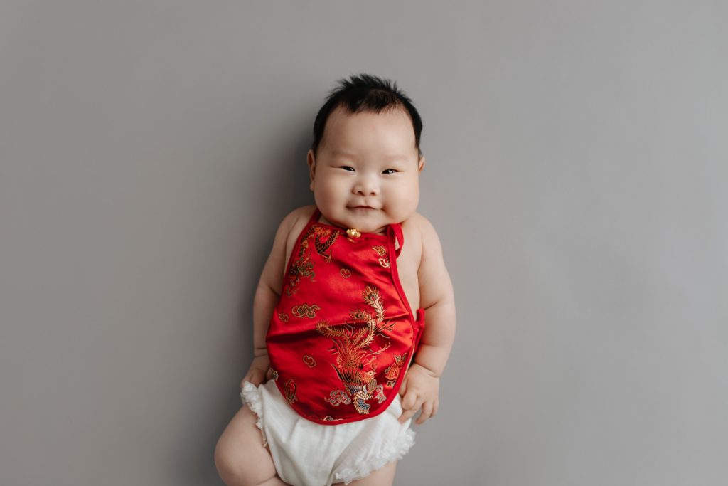 Baby girl wearing red Chinese scarf for 100 Days portrait.