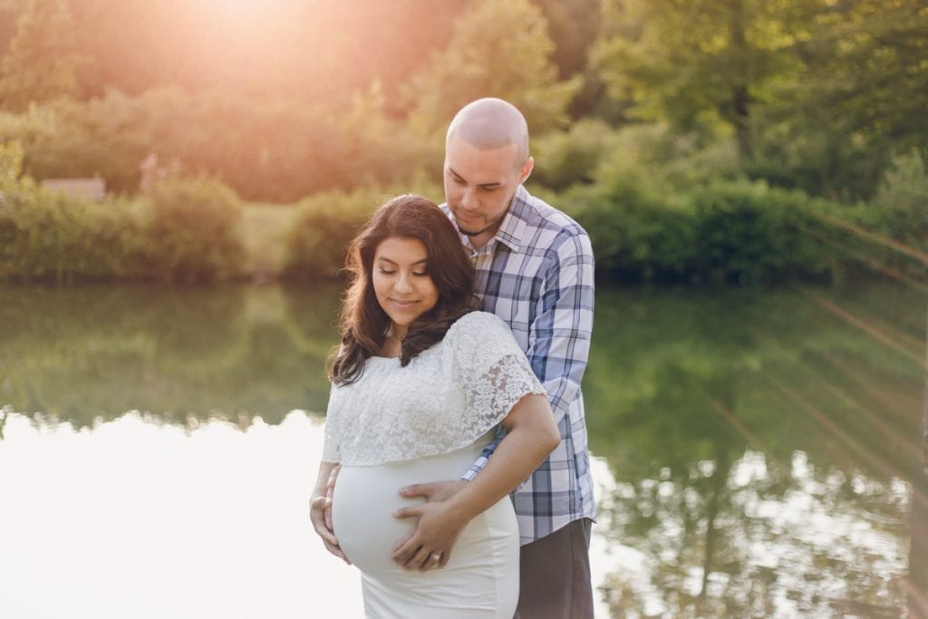 first time expecting parents cradling pregnant belly during their maternity portrait session outdoors during sunset.