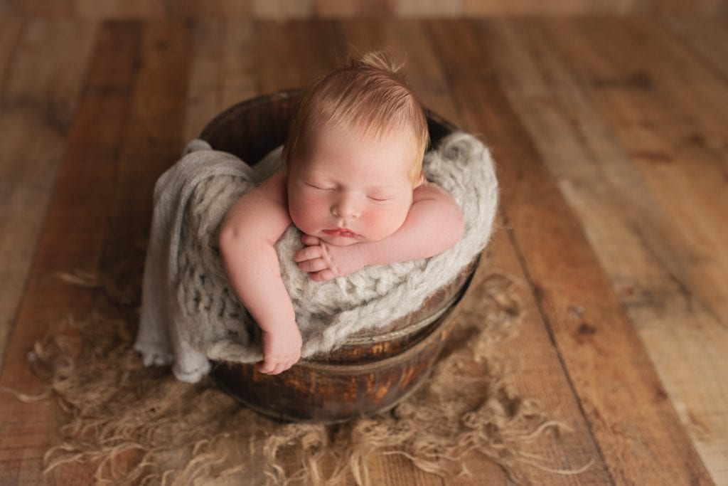 newborn baby boy sleeping in wooden bucket photography prop.