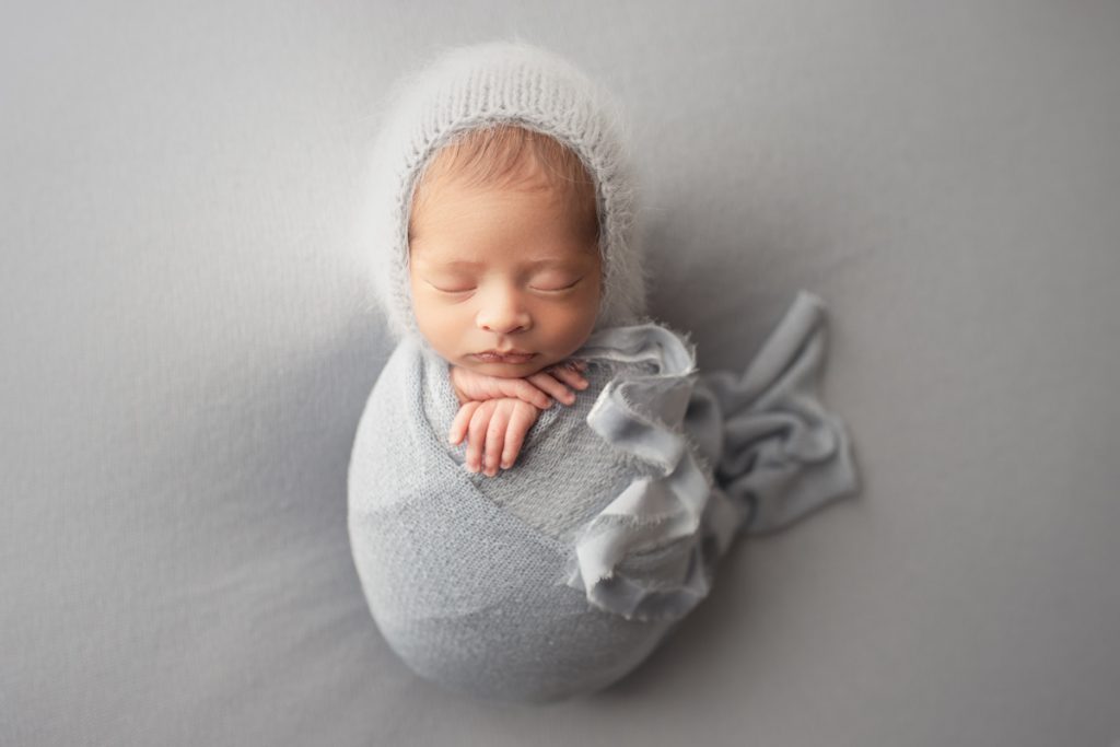 newborn baby boy wearing a fuzzy blue bonnet.