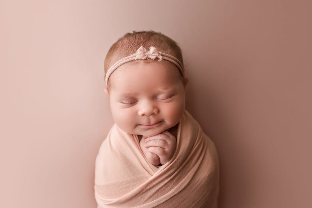 baby girl wearing a pink headband with little pink bow; newborn headband.