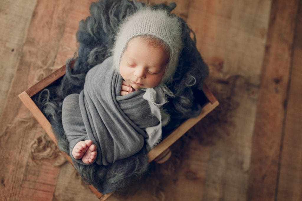 sleeping newborn nestled into a wooden crate photography prop.