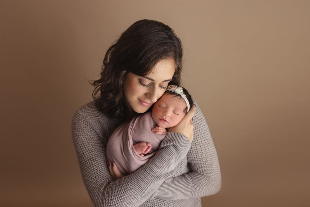 Portrait of mother holding newborn baby girl; studio newborn session at Yvonne Leon Photography