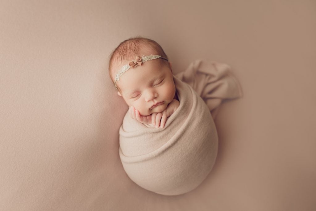 baby girl wrapped in a pink wrap for potato sack pose in newborn photography.