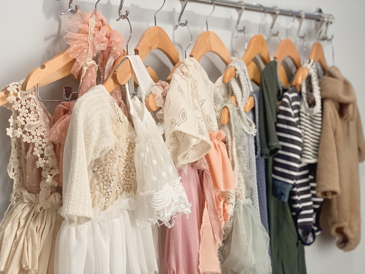 A rack of cute baby clothes for boys and girls in a photo studio to be used as props for baby milestone photo sessions.