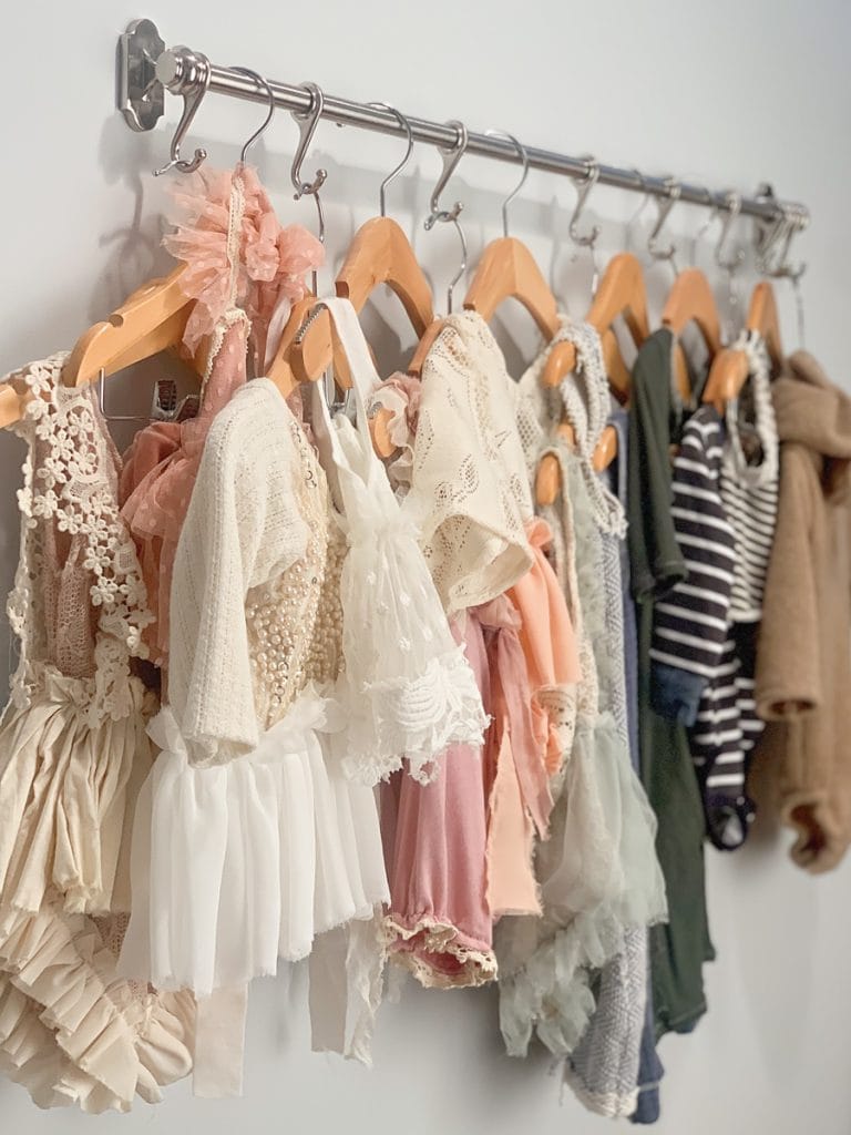 A rack of cute baby clothes for boys and girls in a photo studio to be used as props for baby milestone photo sessions.