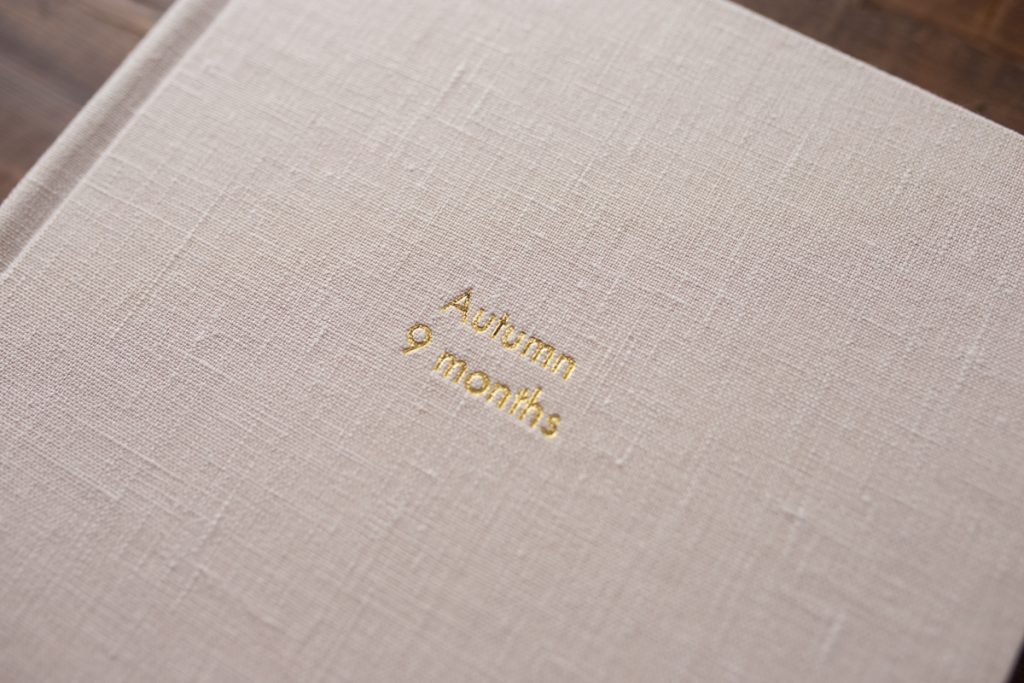 closeup of gold embossing on a linen album cover; text says "Autumn 9 months"