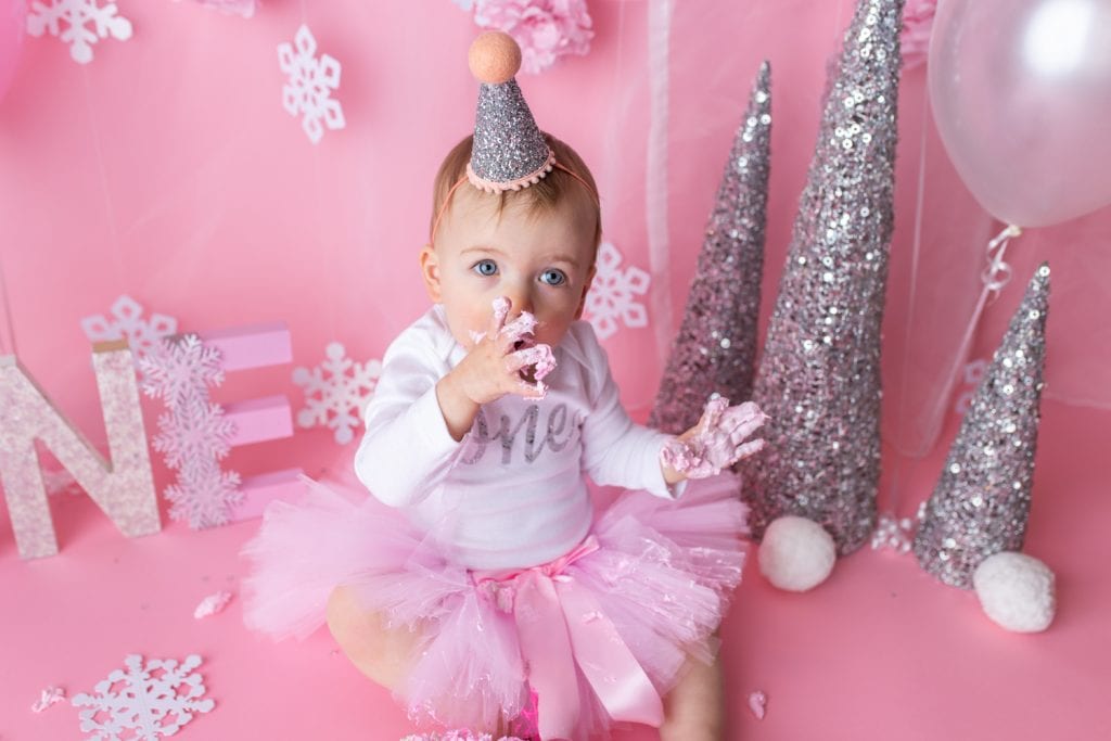 baby hands covered in pink cake frosting.