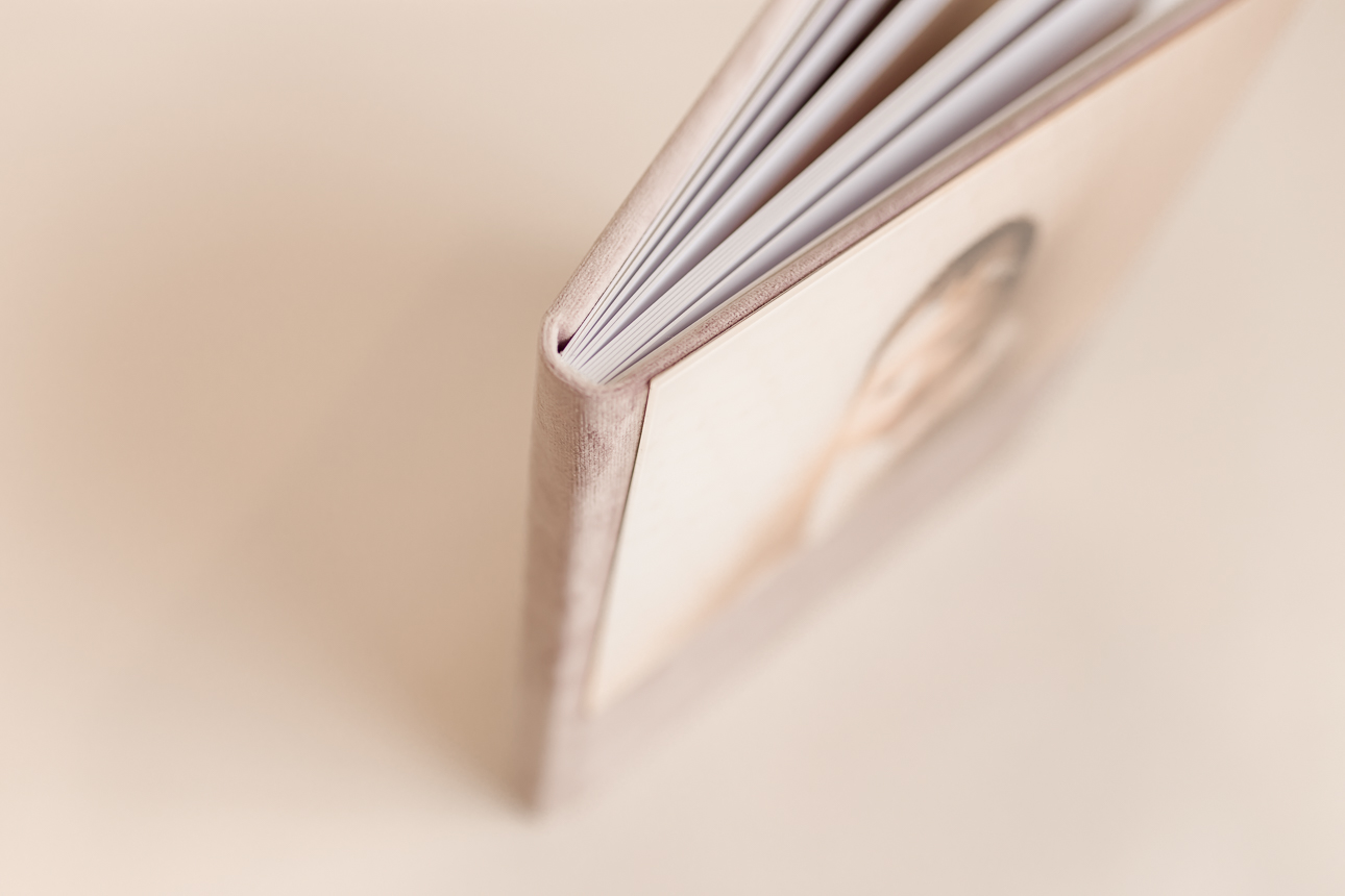 Close-up of portrait album corner showing spine and pages in focus, blurred bokeh on velvet photo cover.
