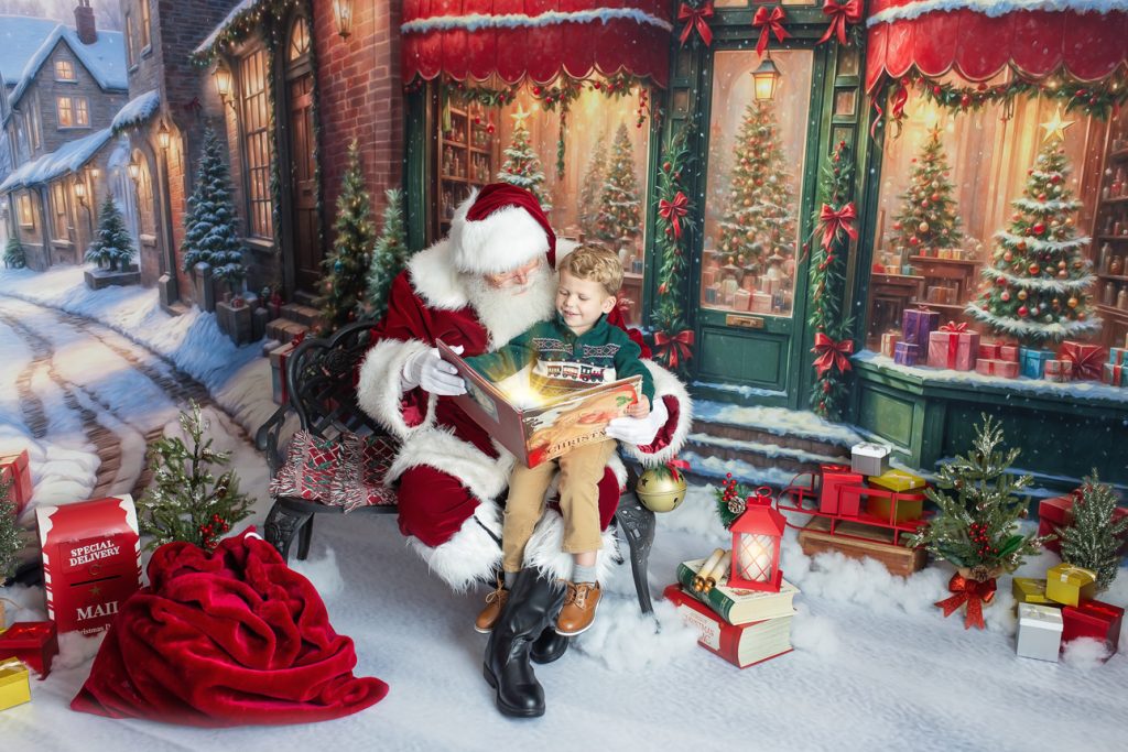 Santa sits on bench in snowy outdoor-style studio scene with little boy on lap as magic dust rises from an opened book.