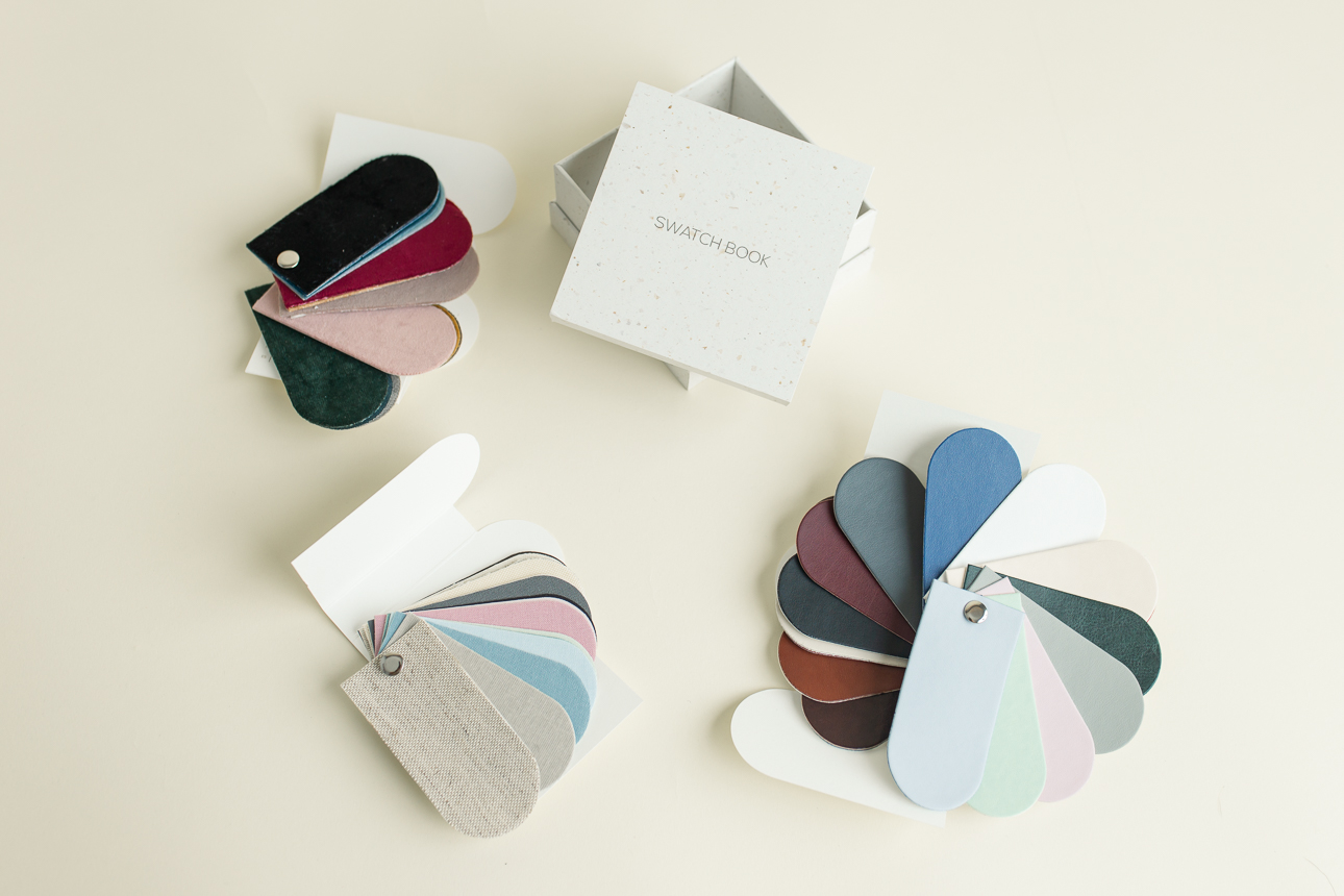 Fabric swatches in different colors and materials, fanned out in three different piles next a box that says "Swatch Book."