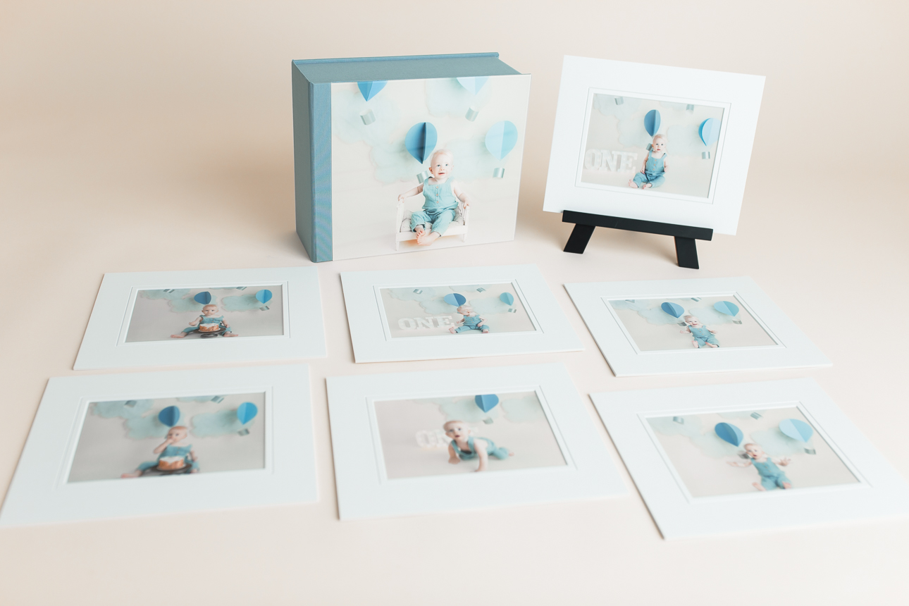 Gallery box with acrylic photo cover surrounded by matted portraits with one displayed on an easel; studio product display.