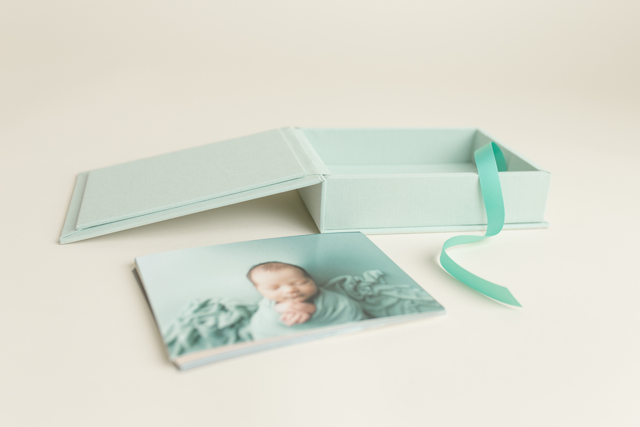 Hinged print box in mint-colored linen shown with a stack of 5x7 prints beside it; studio display of print and gift items.